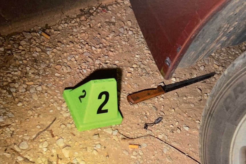 A knife on the ground beneath a car.