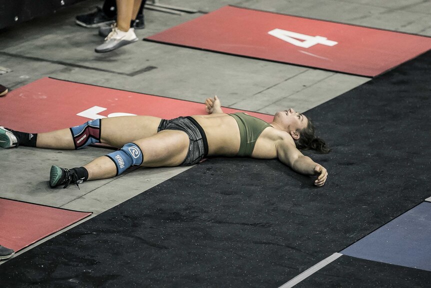 A CrossFit athlete lies on the gym floor exhausted after an event at the 2019 CrossFit Down Under Championships.