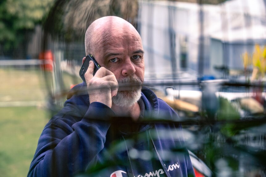 a man on the phone photographed through a bird cage