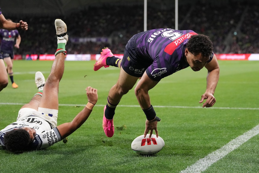 NRL player Xavier Coates is diving, with his fingers on the football, scoring a try.