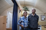 Two people in a converted underground bunker look up at the curved ceiling