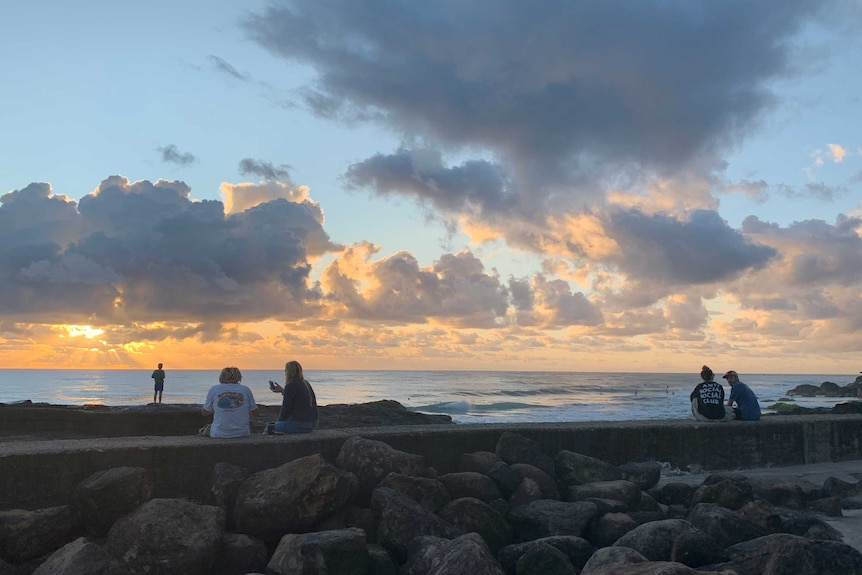 People sit in pairs at Snapper Rocks on the Gold Coast keeping distance between them.