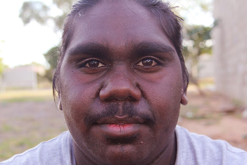 A young Aboriginal man looks directly at the camera