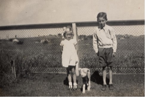 Black and white photo of two children and a lamb.