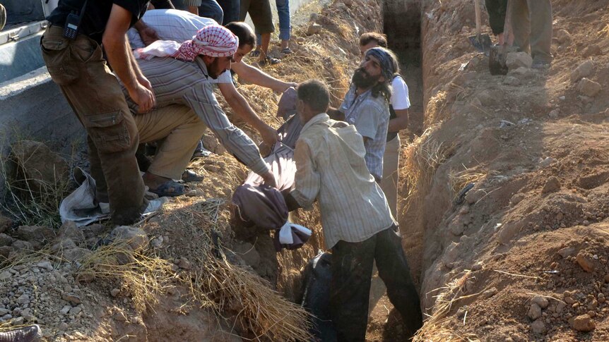 People lower a body into a grave in suburban Damascus