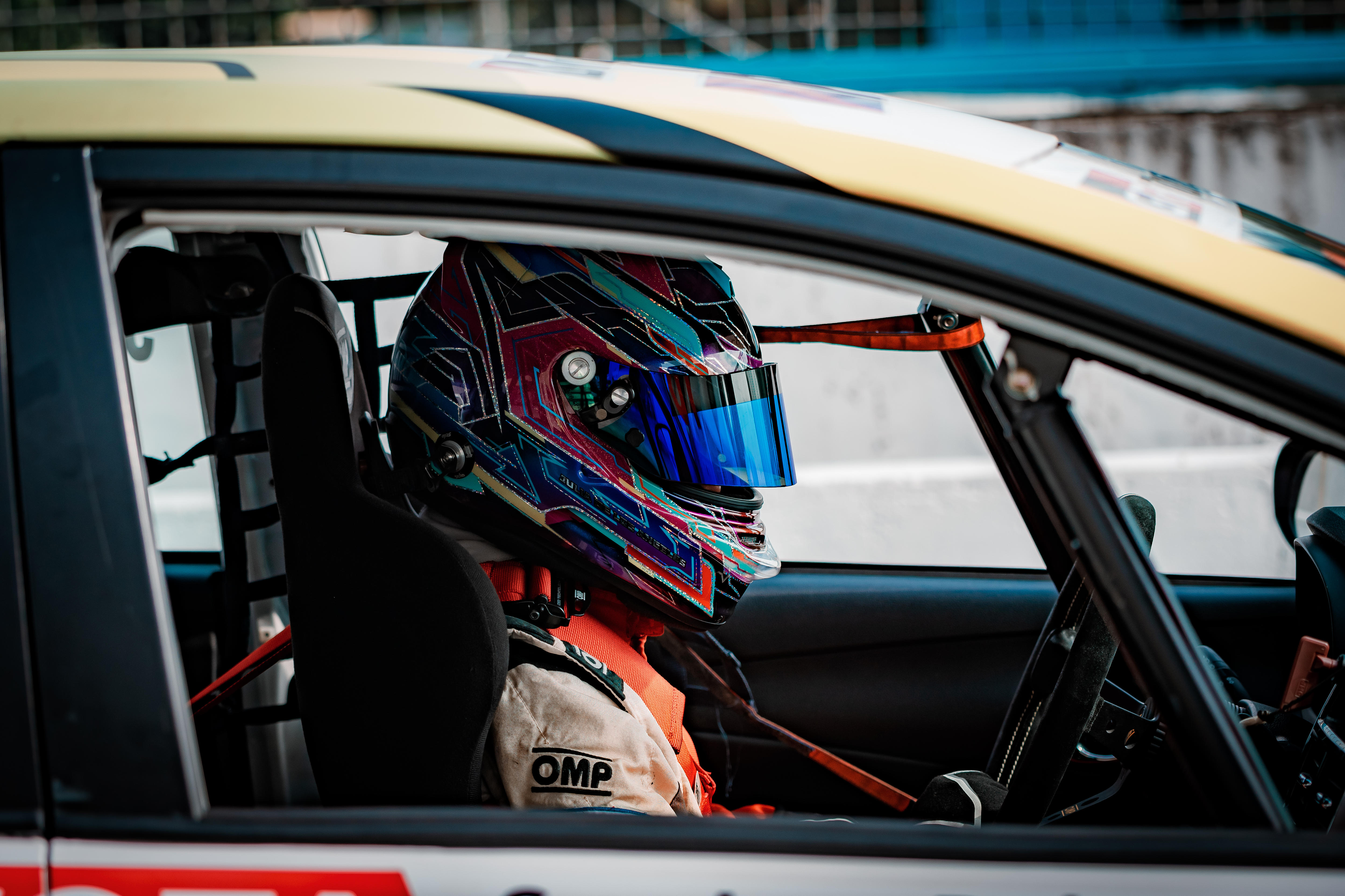 A woman in a racing car with a helmet on.