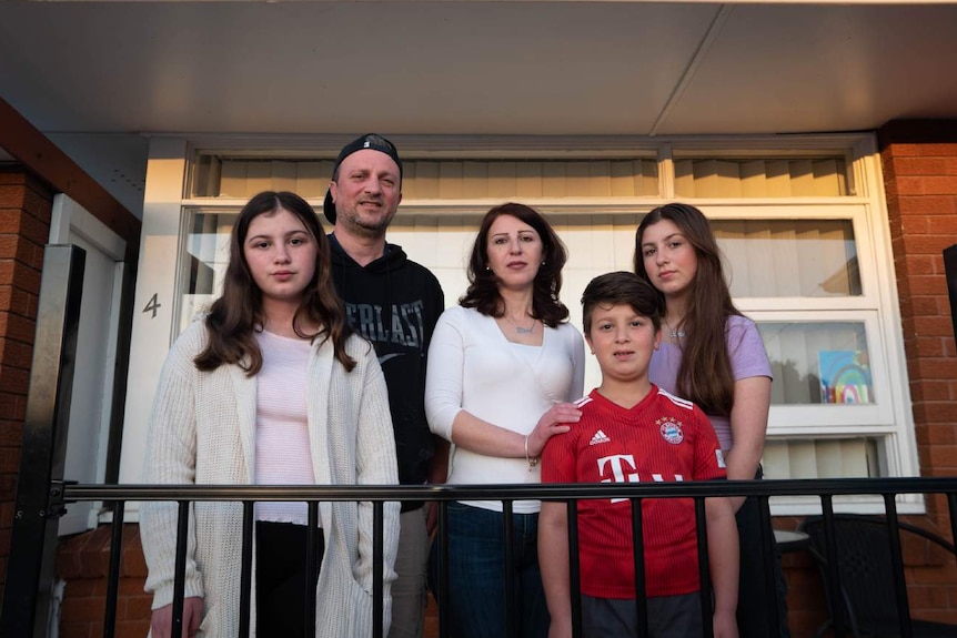 A family stand outside their home