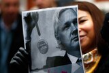 A supporter of Julian Assange holds a poster outside the Ecuadorian embassy in London.