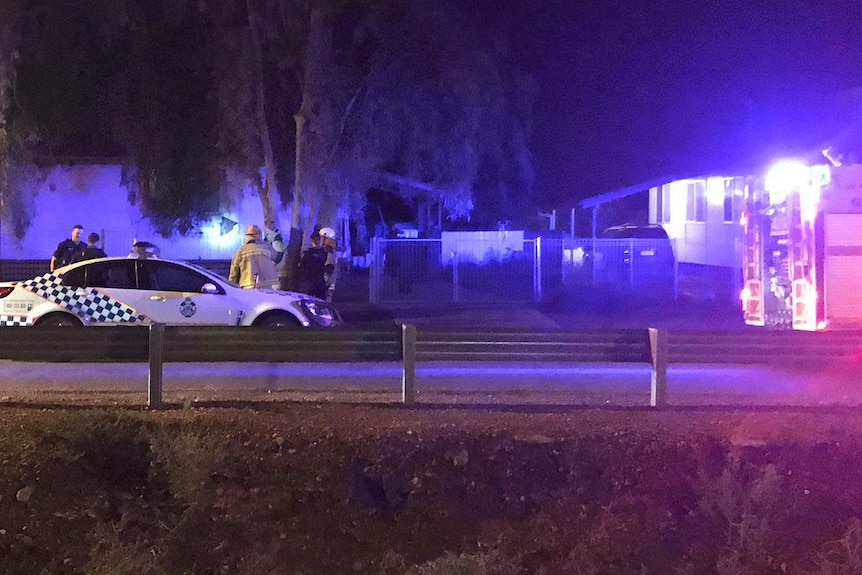 Police and firefighters on the footpath outside a house at night