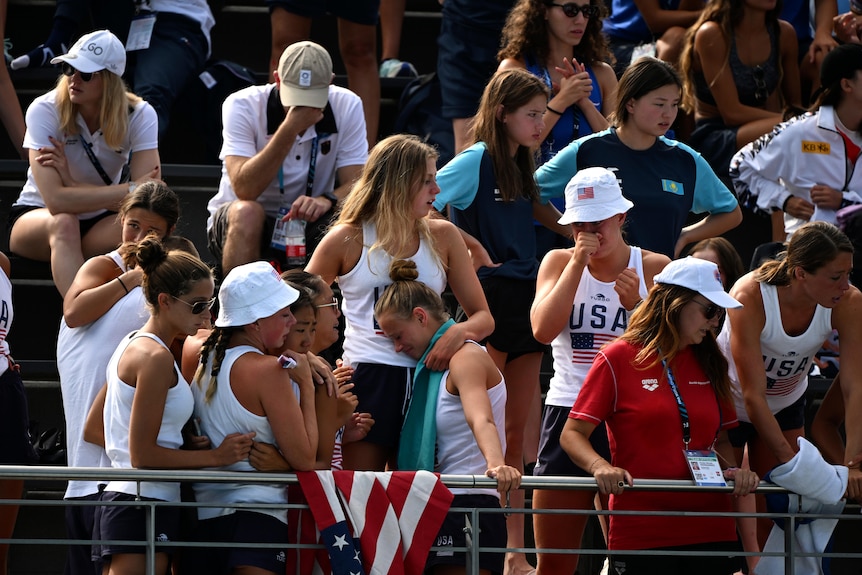 Spectators cry and hold each other as they watch a woman pulled unconscious from the pool.