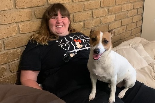 Woman sitting with her legs out with a dog on her lap - small dog, jack russell looking