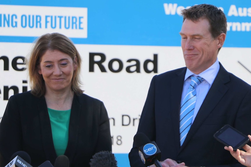 Rita Saffioti and Christian Porter laughing awkwardly in front of a government sign about a road project.