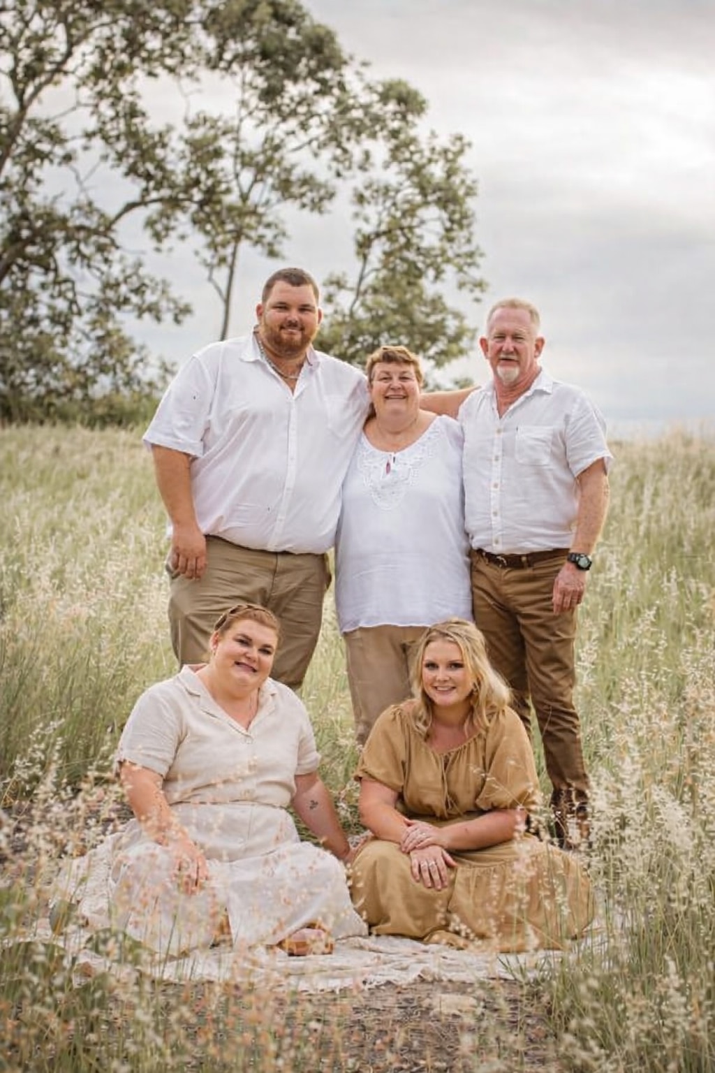 Una familia vestida de blanco posa en un prado.