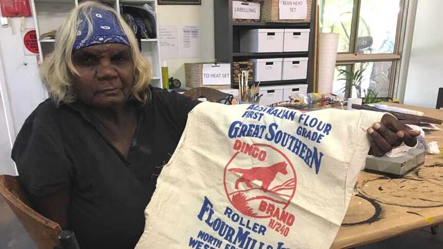 Indigenous artist Phylis Waye from Fitzroy Crossing holds up a Dingo flour bag