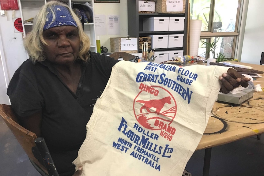 Indigenous artist Phylis Waye from Fitzroy Crossing holds up a Dingo flour bag