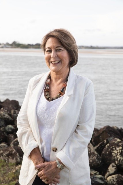 a woman standing in front of the beach and smiling