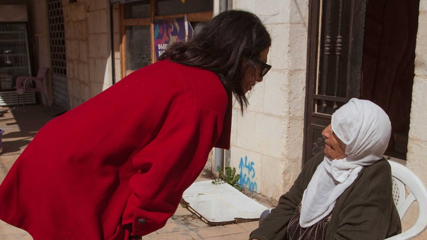 Rima Husseini speaks with an elderly woman.