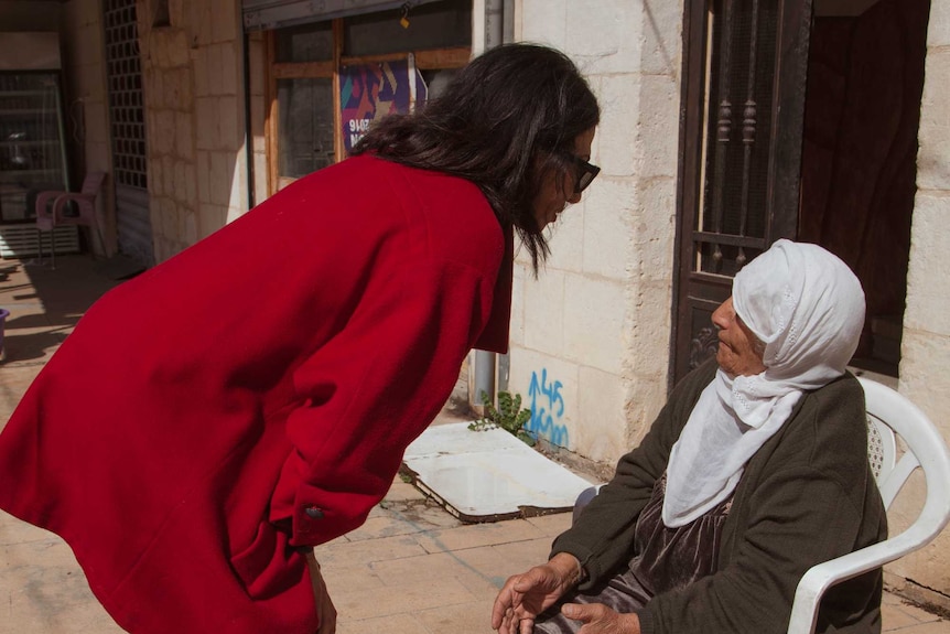 Rima Husseini speaks with an elderly woman.