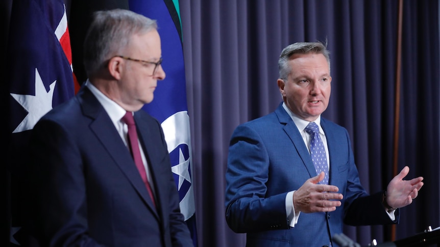 Anthony Albanese listens as Chris Bowen speaks at a press conference 