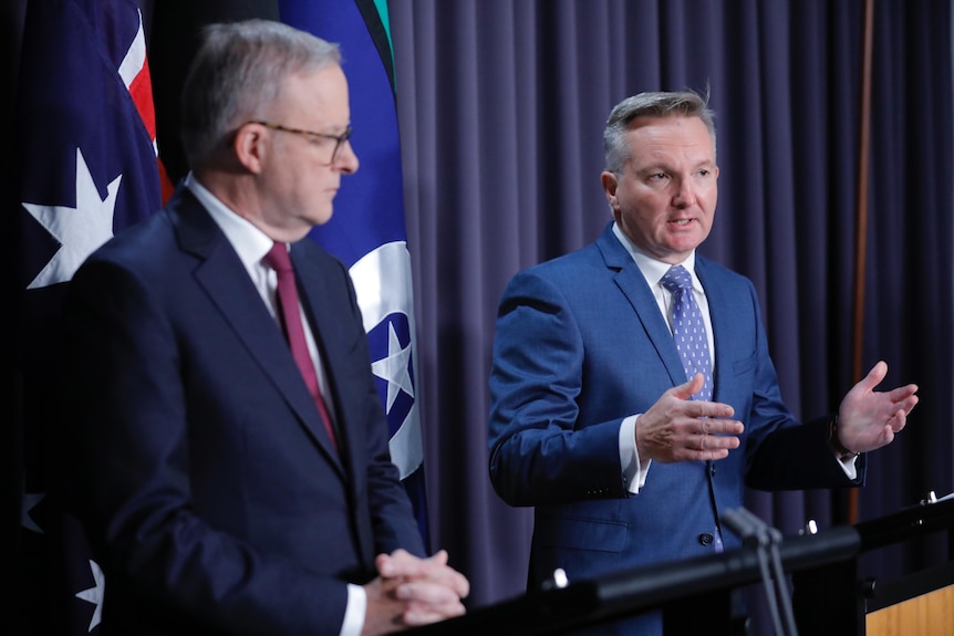 Anthony Albanese listens as Chris Bowen speaks at a press conference 