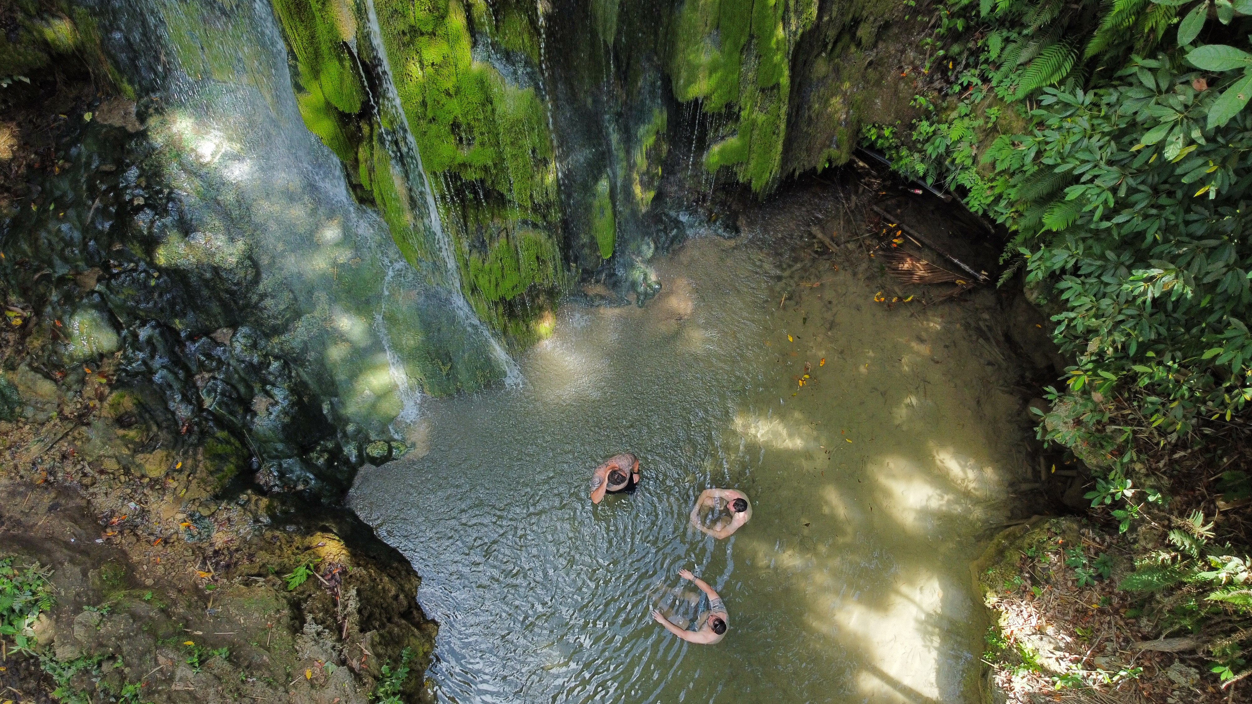 Former soldiers sit in a shallow pool near a waterfall in Timor-Leste. 