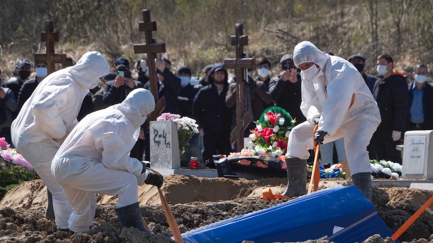Grave diggers wearing protective suits bury a COVID-19 victim.