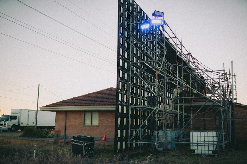 A large LED screen behind an old brick house