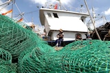 Captain Lin Jianchang mends nets on his trawler.