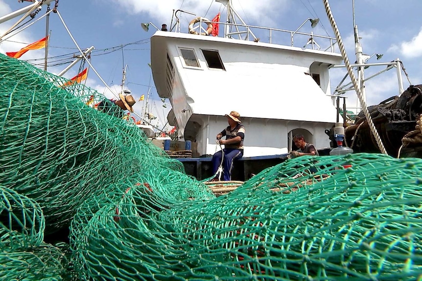 Captain Lin Jianchang mends nets on his trawler.