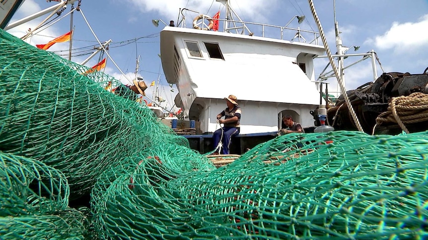 Captain Lin Jianchang mends nets on his trawler.