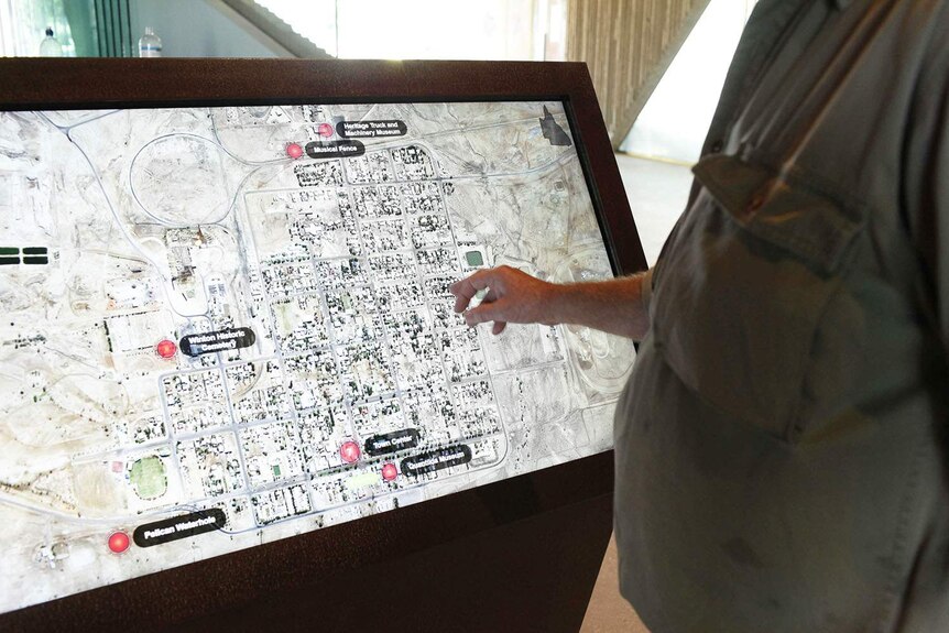 Person touches an interactive map screen in the rebuilt Waltzing Matilda Centre in Winton.