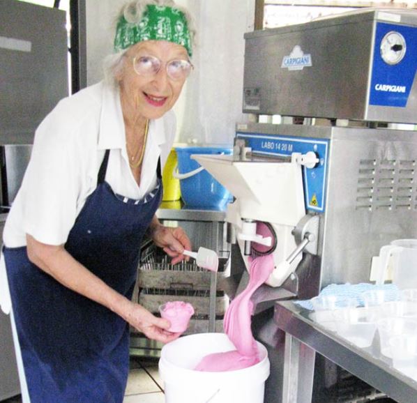 An 89-year-old woman pouring pink ice cream into a bucket.