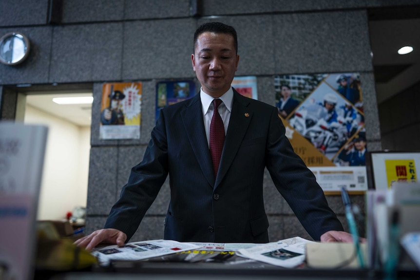 A man in a suit looks at the paper work on his desk