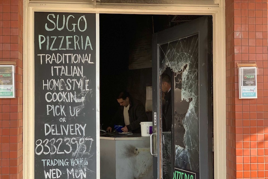 A pizza shop door with its glass smashed in