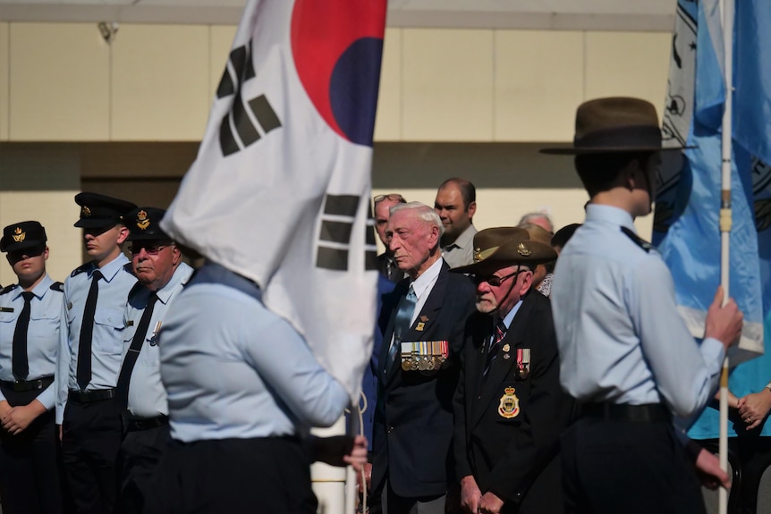 Korean flag in foreground, with two senior men wearing war medals in centre