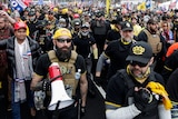 hundreds of men, mostly in sunglasses and masks and yellow and black caps in bandanas, marching