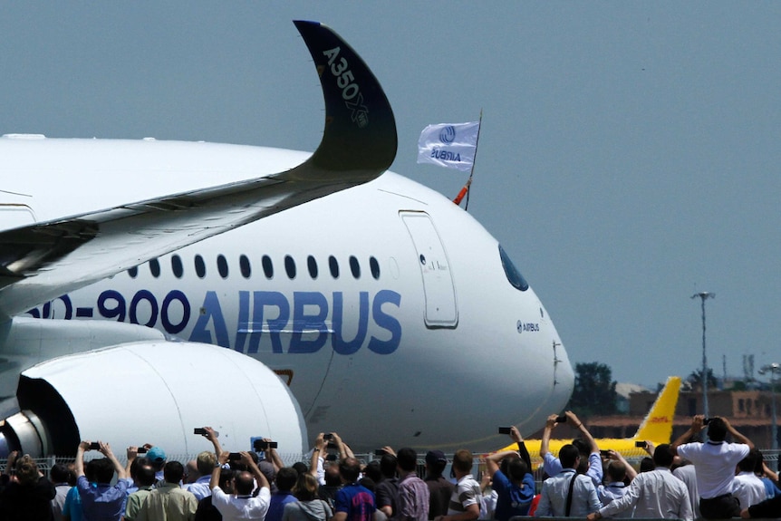 A pilot waves a flag and employees take pictures after the new Airbus A350's maiden flight.