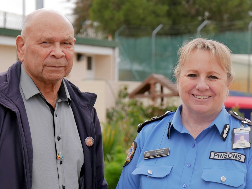 A woman wearing police uniform with a man standing out the front of a prison.