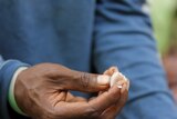 A man's hand holds a fresh cocoa bean.