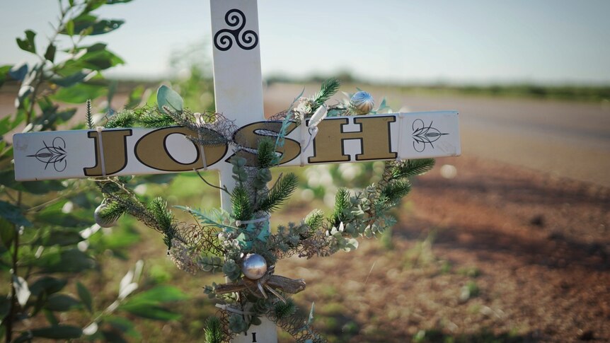 A roadside memorial, a cross with the words Josh on it 