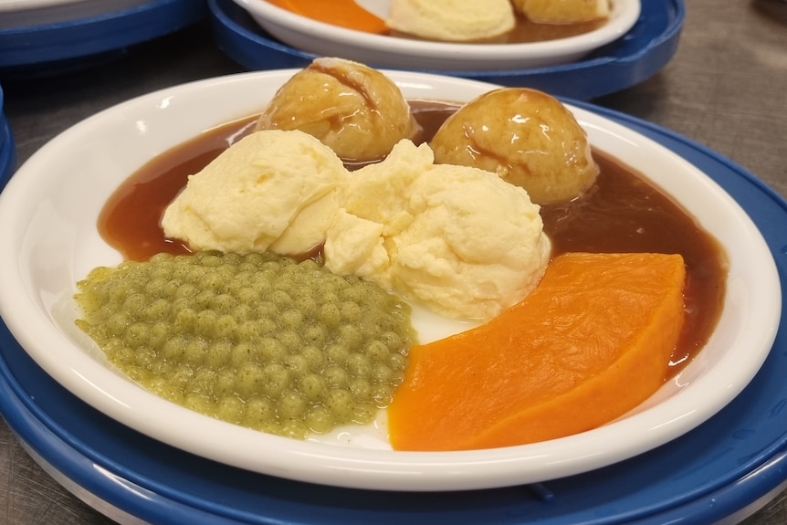 Un plato de guisantes, puré de patata, calabaza y salsa en un plato.