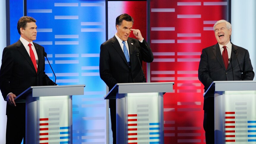Rick Perry speaks while former Massachusetts Governor Mitt Romney and former speaker of the House Newt Gingrich react
