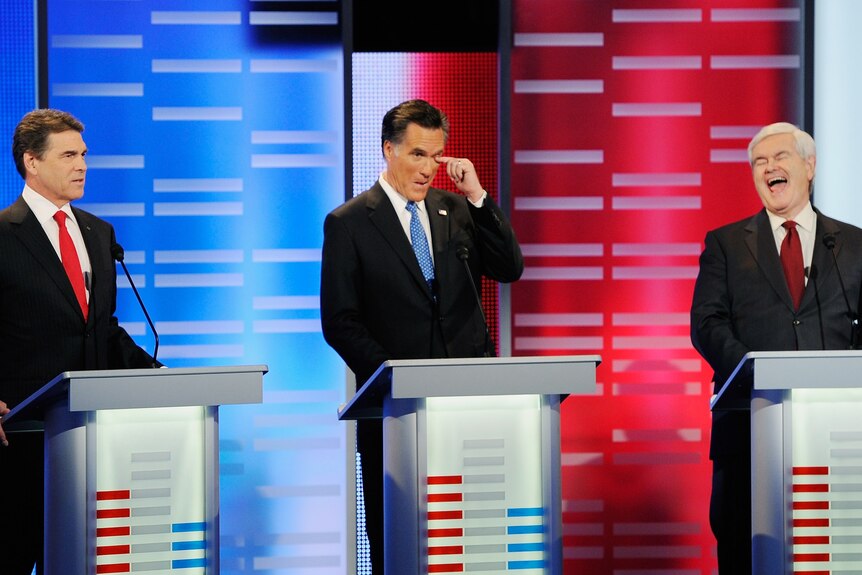 Rick Perry speaks while former Massachusetts Governor Mitt Romney and former speaker of the House Newt Gingrich react