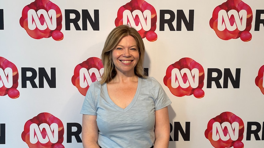 woman smiles brightly at the camera in front of an RN background