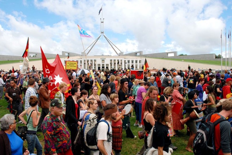 Thousands of people march across the front of Paliament House protesting against the