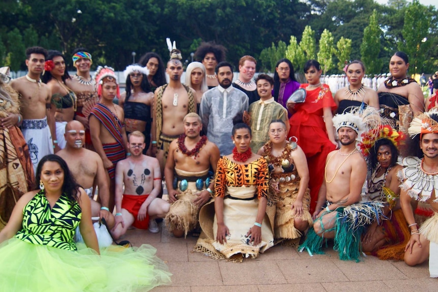 Twenty-six members of Runway Movement pose for a group photo. All are dressed in contemporary Pacific attire.