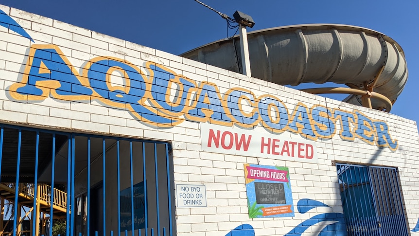 A white brick wall with AquaCoaster painted in blue and yellow letters. 