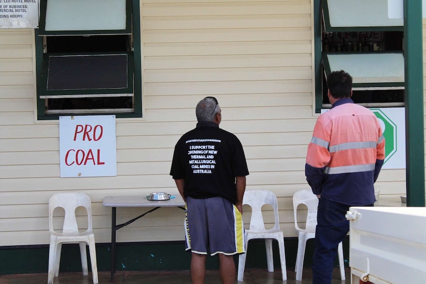 Two locals look at pro coal and other signs against protesters at the Clermont pub.