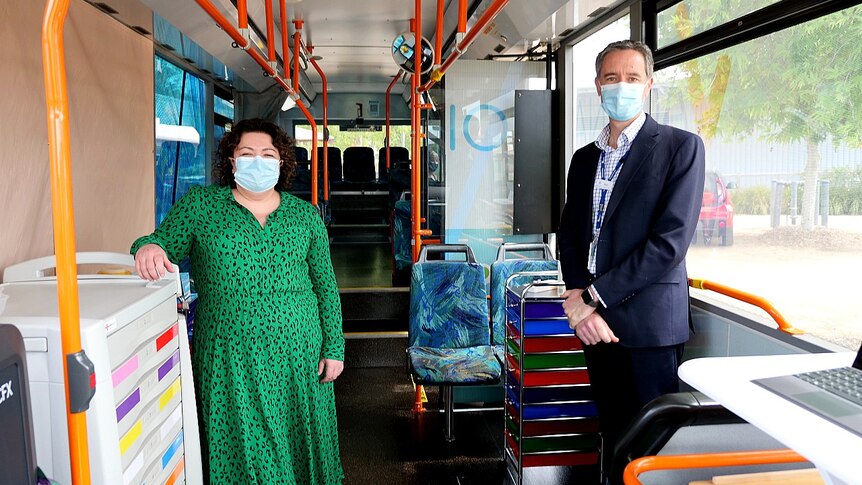 A woman and man wearing masks standing in a bus
