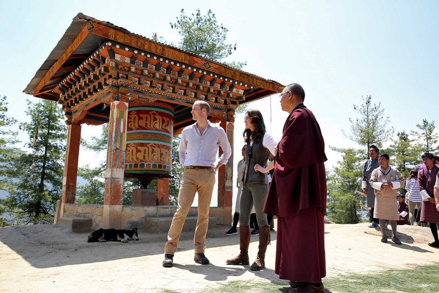 Prince William, Catherine and the director of Bhutan's national museum stand in front of monastery.